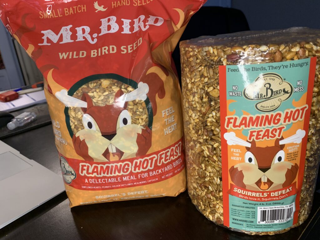 A bag and cylinder of Flaming Hot Feast spicy bird seed. This is great at slowing squirrels down.