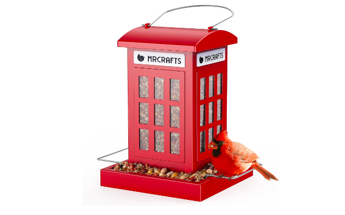 A bird feeder that's shaped like a red phone booth with a Northern Cardinal sitting in it. 