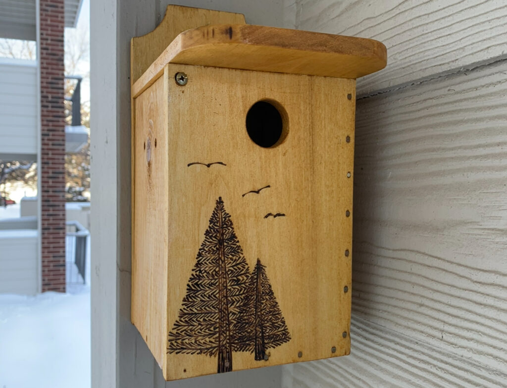 A bird house hanging outside in the winter.