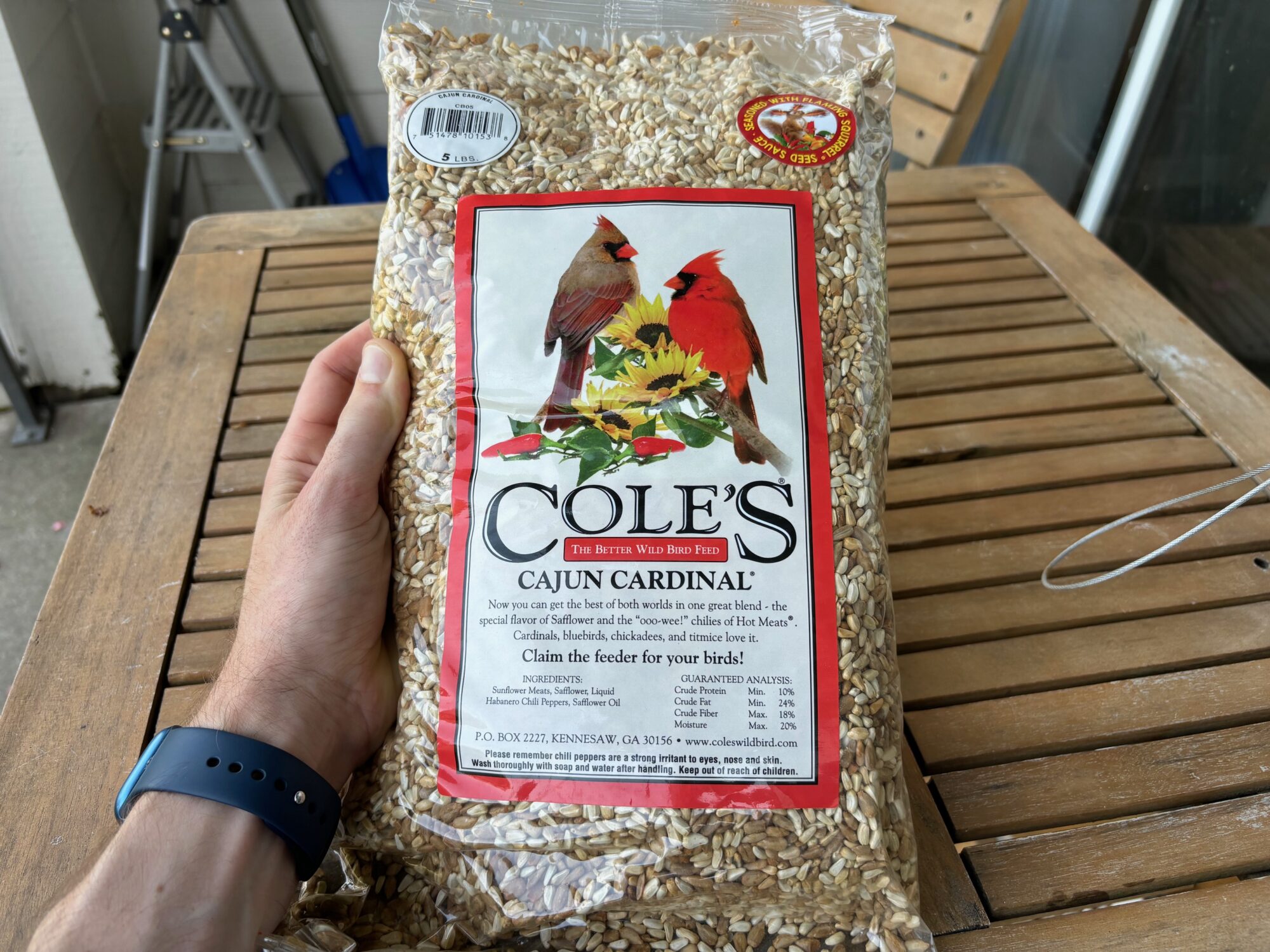 A bag of spicy bird seed on a picnic table.