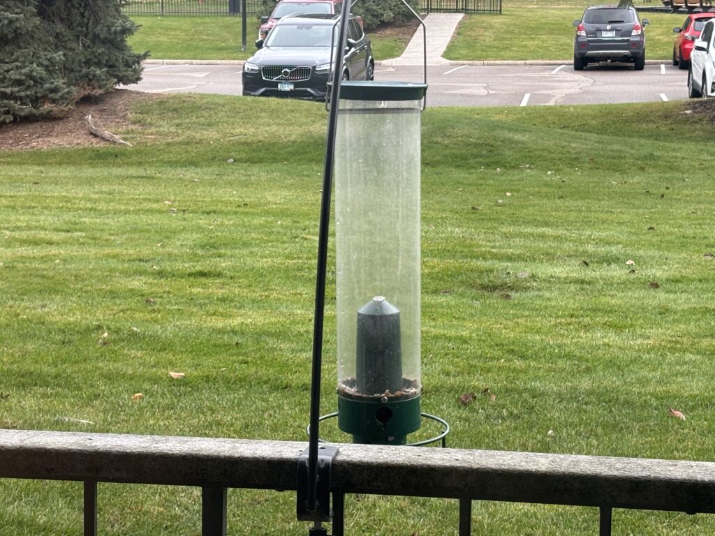 A Droll Yankee Flipper bird feeder hanging from an apartment balcony. 
